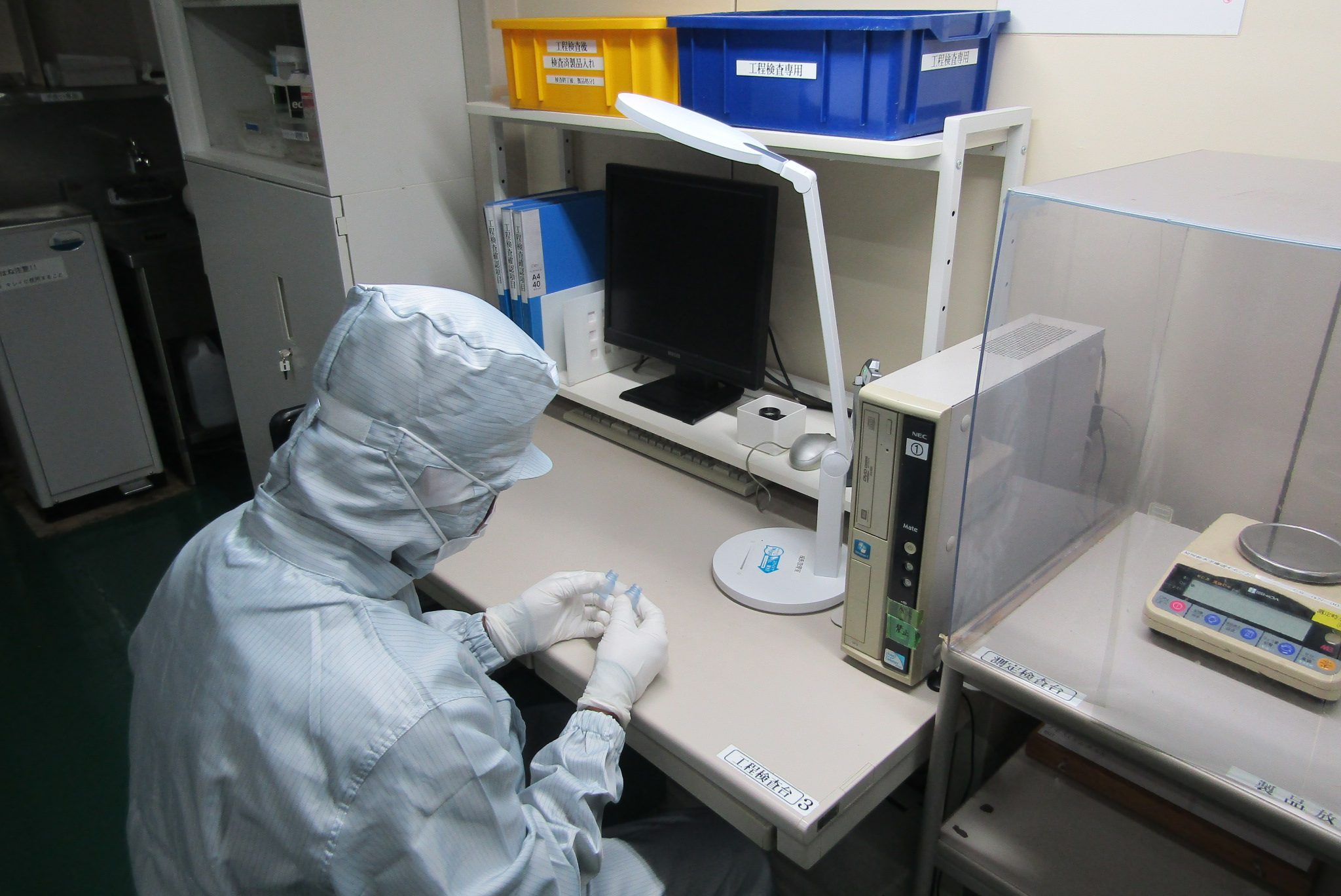工程検査台で、作業者が容器を手に取って確認している